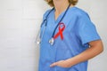 Wonan doctor with a stethoscope on shoulder holding red ribbon