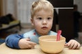 Wonder struck boy by the empty brown saucer with pink spoon