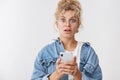 Wondered amazed cute blond woman messy curly bun wearing glasses denim jacket playing cool smartphone game holding phone