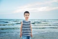 Wondered amazed cute boy in a striped T-shirt at the seaside questioned surprised. Summer vacation. happy kid playing on beach at