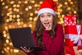 Wondered happy cute girl in santa claus hat using laptop Royalty Free Stock Photo