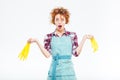 Wondered housewife holding yellow gloves in both hands