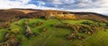 Wonderful autumn colored forest, setting sun with dramatic sky, valley with green grass and trees. Sunlight nature landscape