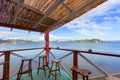 A wonderful beach bar. The view from the bar with its reed roof and weathered wooden floor over the wooden stools to the calm sea Royalty Free Stock Photo