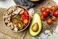 A wonderful canned tuna salad with diced tomatoes and avocados in a golden bowl with pepita tomatoes and avocado over dried