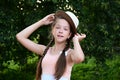 wonderful cheerful young girl with two braids and hat poses against background of green foliage. Royalty Free Stock Photo