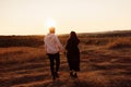 Wonderful couple walking at the field, attractive husband holding hands adorable wife, overjoyed woman smiling, happy