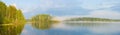 A wonderful evening in fog on the lake, pink clouds in the sky are reflected with trees from the water surface