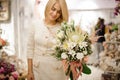 wonderful exclusive bouquet of different white flowers decorated with greenery in hands of blonde woman