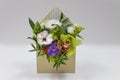 Wonderful floral arrangement of fresh flowers in a box in the form of an envelope on a light background.