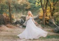 Wonderful lady in blond curly hair in a gray luxurious flying gorgeous and fluttering wedding dress with flowers, mesh Royalty Free Stock Photo