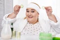 Delighted fat woman making a cucumber mask
