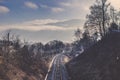 Railway track among trees line and winter mountain range Royalty Free Stock Photo