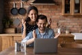 Excited young family couple laugh splash hands by pc screen