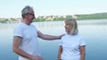 A wonderful senior man and an old woman walking in the park near the pond. Active healthy retired couple talking Royalty Free Stock Photo