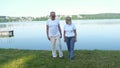 A wonderful senior man and an old woman walking in the park near the pond. Active healthy retired couple talking Royalty Free Stock Photo