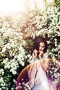 Wonderful spring. Beautiful young girl enjoys nature and sunlight among the blossoming spirea.