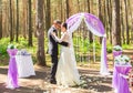 Wonderful stylish rich happy bride and groom dancing at a wedding ceremony in green garden near purple arch with flowers Royalty Free Stock Photo