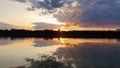 Wonderful sunset over the city horizon with reflection on the calm lake water in a silent summer evening