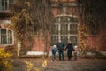 A wonderful sweet family stands near an old brick house in the fall, they hold hands and smile. Soft focus