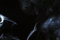 Wonderful swirl contrast blue smoke against dark background. Royalty Free Stock Photo