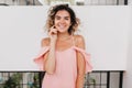 Wonderful tanned girl in summer pink outfit touching her face. Portrait of slim laughing young woma Royalty Free Stock Photo