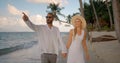 Wonderful tropical ocean beach in the evening, young couple walking hand in hand near the water Royalty Free Stock Photo