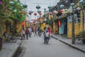 Wonderful view of old street decorated with colorful silk lanterns. Vietnamese people in traditional closes walking