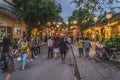 Wonderful view of old street decorated with colorful silk lanterns. Vietnamese people in traditional closes walking