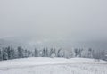 Wonderful winter scene with snow falling. Bukovel ski resort in Ukrainian Carpathians. Snowy forest on the mountain hills. Foggy Royalty Free Stock Photo