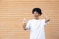 A wonderfully American man holding a white ice cream cone on an outstretched arm with hand in hair