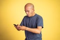 Wondering asian bald man looking at smartphone