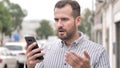 Wondering Beard Casual Man Shocked by Results on Phone Royalty Free Stock Photo
