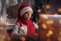 A wondering boy sitting in front of laptop wearing red Santa cap having Christmas skype meeting. Royalty Free Stock Photo