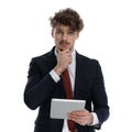 Wondering businessman holding tablet and hand on chin Royalty Free Stock Photo