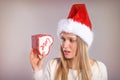 Wondering Christmas woman with a Santa hat holding a gift box Royalty Free Stock Photo