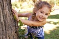 They wont find me here. Portrait of a little girl hiding behind a tree in a park. Royalty Free Stock Photo