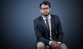 He wont lose focus. Studio portrait of a handsome young businessman sitting on a chair against a dark background. Royalty Free Stock Photo