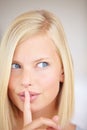 She wont tell if you dont. Portrait of a young woman holding her finger in front of her lips. Royalty Free Stock Photo