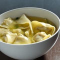 Wonton soup in a white bowl.