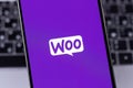 WooCommerce (Woo) logo on a screen smartphone iPhone. WooCommerce is an open-source e-commerce plugin for WordPress