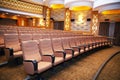 wood armed formal plush deep red velvet opera movie theater chairs in curved row with decorative gold molding in fancy carpeted Royalty Free Stock Photo