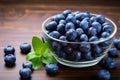 Wood background accents a glass bowl of plump, organic blueberries