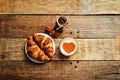 Wood background with cappuccino, croissants, cinnamon and jar of