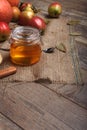 Wood background with colorful apples, a glass jar of honey, and a spoon on a ustic napkin, close-up. Autumn harvest
