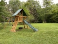 Wood backyard playset with wave slide, two clubhouses, rock climbing wall, swings with tire swing, an access ladder