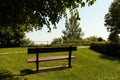 wood bench on grass with no one sitting on it surrounded by trees, over looking