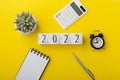 2022 wood block with calculator and notebook on yellow background Royalty Free Stock Photo