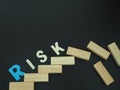 Wood block stacking as step stair with colorful of risk word on it in black background. Some of wood block on top are fallen which Royalty Free Stock Photo