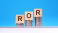 ror - text on wood cubes stack with coins